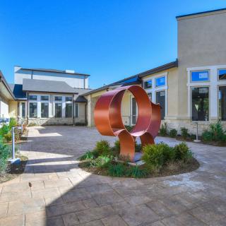 A modern courtyard featuring an abstract metal sculpture surrounded by a well-maintained landscape.