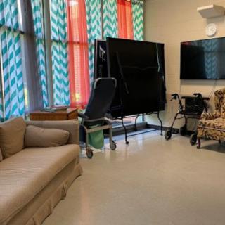 A cozy living room with colorful curtains, a couch, armchair, and a television.