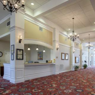 A spacious and elegantly designed hotel lobby featuring a reception desk, chandeliers, and decorative carpet.