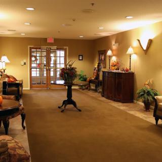 A warmly lit lobby area with furniture, plants, and decorative elements.