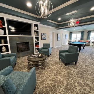 A modern living room with comfortable seating, a fireplace, and a pool table.