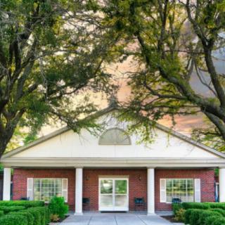 A building entrance surrounded by lush green trees.
