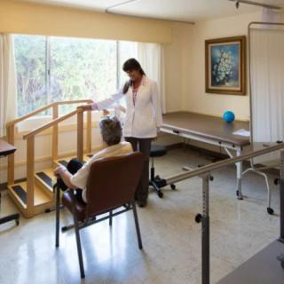 A therapist assisting a patient in a physical therapy clinic with various exercise equipment.