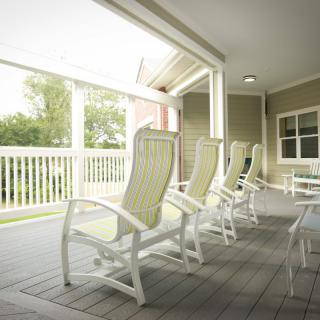 A row of comfortable chairs on a bright, covered porch.
