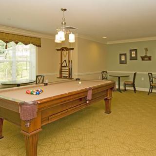 A well-lit game room featuring a billiards table and seating area.