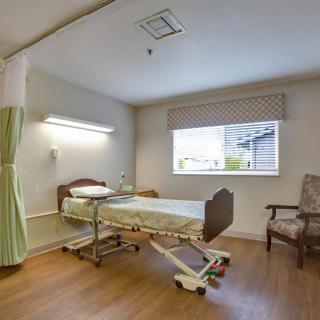 An empty hospital room with a single bed and a chair.