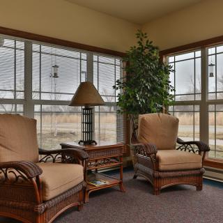 A cozy living room with armchairs and large windows offering a view outside.