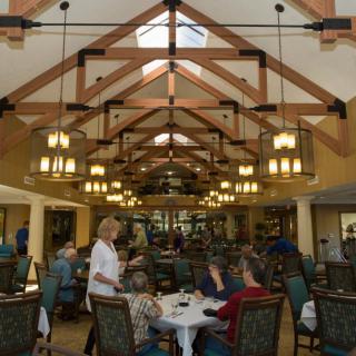 A spacious dining hall with wooden beams, elegant lighting, and patrons enjoying their meals.