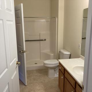 A clean and simple bathroom with a shower, toilet, and sink.