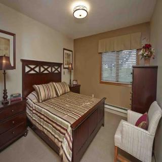 A cozy bedroom with a wooden bed, bedside table, and a chest of drawers.
