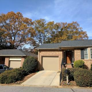 A brick house with a driveway and garage surrounded by autumn trees.
