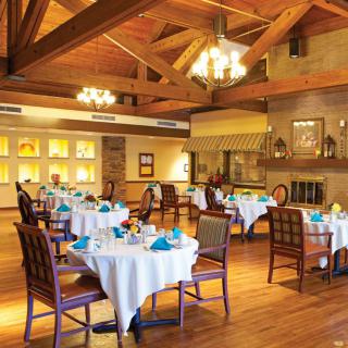An elegant dining room featuring neatly arranged tables with blue napkins and a warm, inviting ambiance.