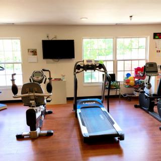 A home gym setup featuring a treadmill, stationary bike, and various exercise equipment in a well-lit room.
