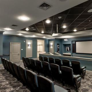 A modern home theater with tiered seating and a large screen.