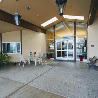 A welcoming entrance to a modern building, featuring outdoor seating and natural light.