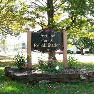 A sign for Portland Care & Rehabilitation surrounded by greenery.
