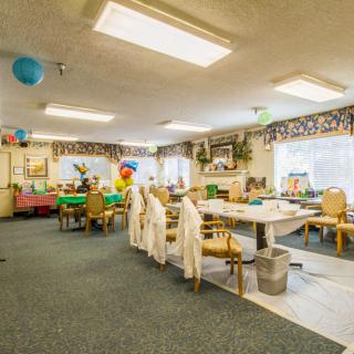 A decorated classroom with tables, chairs, and colorful balloons.