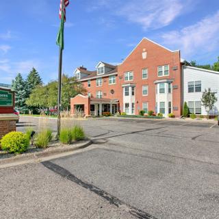 Entrance view of a hotel featuring brick architecture and lush landscaping.