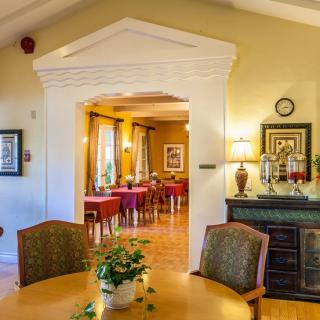 A cozy dining room with elegantly set tables and warm lighting, featuring tasteful decor and plants.