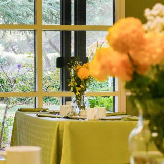 A beautifully set dining table with floral decorations near a large window.