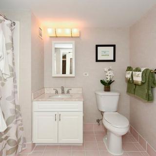 A clean and modern bathroom featuring a sink, toilet, and shower with green towels as decor.