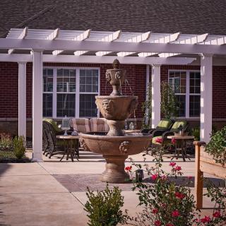 A beautiful courtyard featuring a fountain surrounded by a pergola and garden seating.