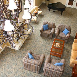 A hotel lobby with comfortable seating, a chandelier, and a grand piano.