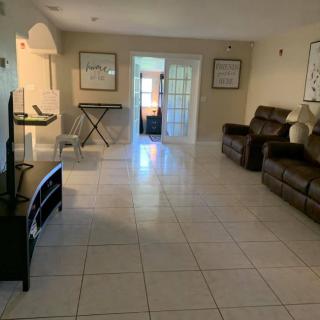 A spacious living room with tiled flooring, featuring a sofa, television, and elegant decor.