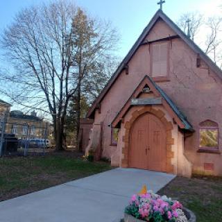 A charming church with wooden doors and a beautiful flower arrangement at its entrance.