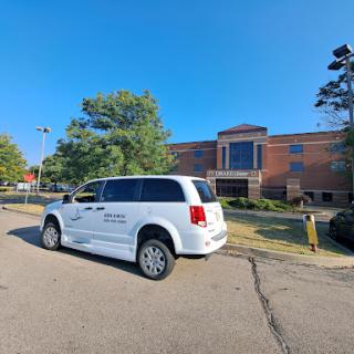 A white minivan parked outside a brick building under a clear blue sky.
