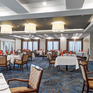 An elegant dining room with neatly arranged tables and chairs, featuring tasteful lighting and decor.
