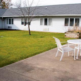 A backyard with a grassy lawn, patio, and outdoor seating.