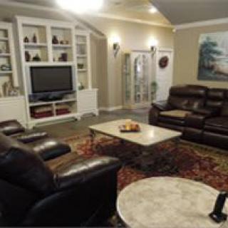 A cozy living room with leather sofas, a television, and decorative shelving.