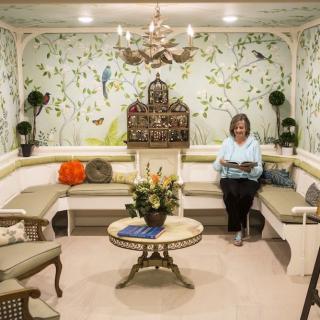 A cozy sitting area with elegant wallpaper and floral decor.