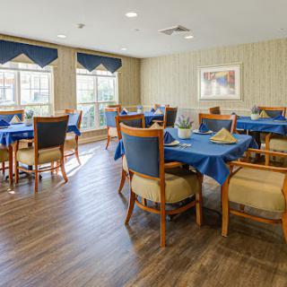 A well-lit dining area featuring wooden furniture and blue table settings.