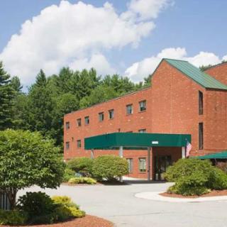A brick building with a green roof surrounded by trees and a clear sky.