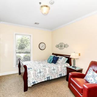 A cozy bedroom with a bed, red armchair, and decorative elements.