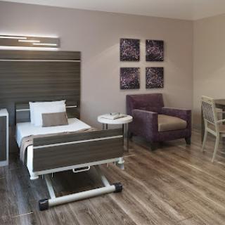 A modern hospital room featuring a patient bed, comfortable seating, and stylish decor.