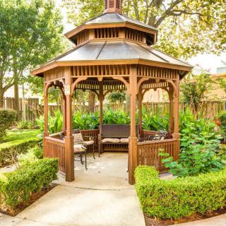 A charming wooden gazebo nestled in a lush garden setting.