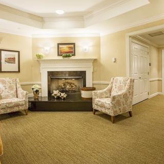 A cozy living room with two armchairs facing a decorated fireplace.