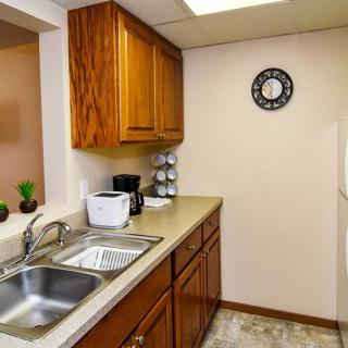 A compact kitchen with wooden cabinets, a double sink, and essential appliances like a coffee maker and microwave.