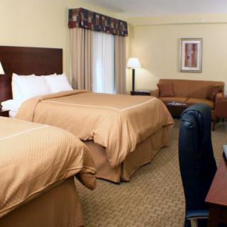 A cozy hotel room with two comfortable double beds and warm lighting.