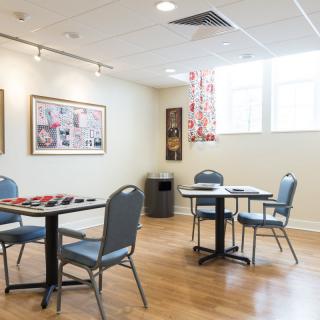 A well-lit meeting room with tables and chairs, decorated with art on the walls.