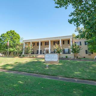 A view of a charming two-story building surrounded by greenery.