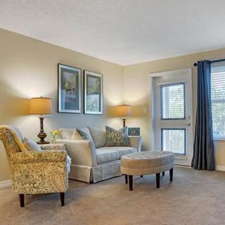 A cozy living room with a sofa, armchairs, and warm lighting.