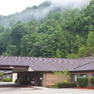 A building set against a backdrop of foggy mountains and dense green trees.