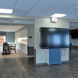 A modern office space with a conference room and a large television screen.