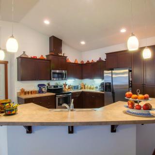 A modern kitchen with dark cabinets, stainless steel appliances, and decorative accents on the countertop.
