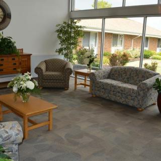 A cozy living room with sofas, chairs, and a coffee table adorned with plants and flowers.