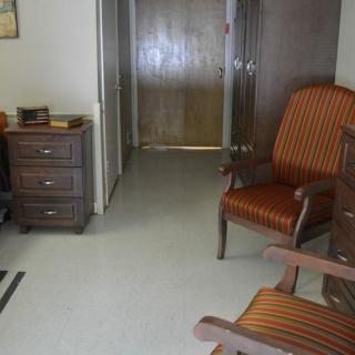 A small office space with a desk, chairs, and wooden furniture.